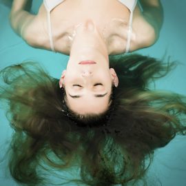 Wellness - young woman floating in Spa or swimming pool, she is very relaxed